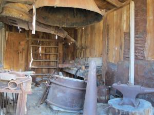 The Stuart Kirkwood Livery Stable and blacksmith shop. Note the size of the bellows behind the hood. Many wagons and literally hundreds of horses, mules and other draft animals were required to haul in tons of goods daily.